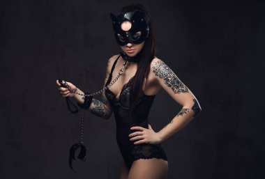 Bdsm kedi deri maske ve karanlık bir arka plan üzerinde poz aksesuarlar siyah iç çamaşırı giyen sıcak esmer metresi kız. 