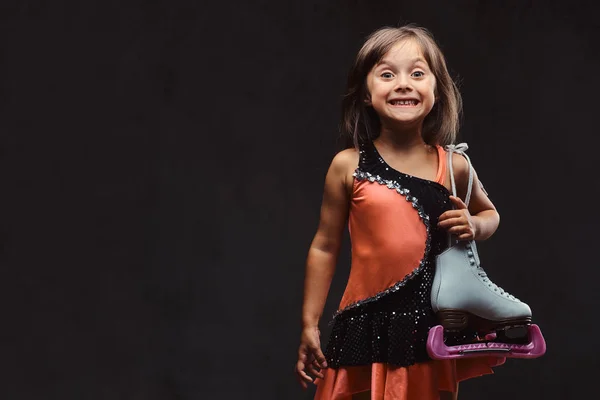 穿着溜冰裙的快乐小女孩抱着溜冰鞋 在深色纹理背景下隔离 — 图库照片
