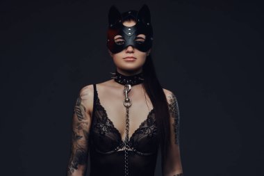 Bdsm kedi deri maske ve karanlık bir arka plan üzerinde poz aksesuarlar siyah iç çamaşırı giymiş seksi kadın. 