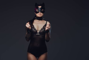 Bdsm kedi deri maske ve kelepçeli aksesuarlar siyah iç çamaşırı giyen kelepçeli sıcak esmer metresi kız.