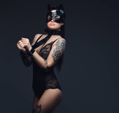 Bdsm kedi deri maske ve koyu arka plan üzerinde poz aksesuarlar siyah iç çamaşırı giymiş seksi kadın. 
