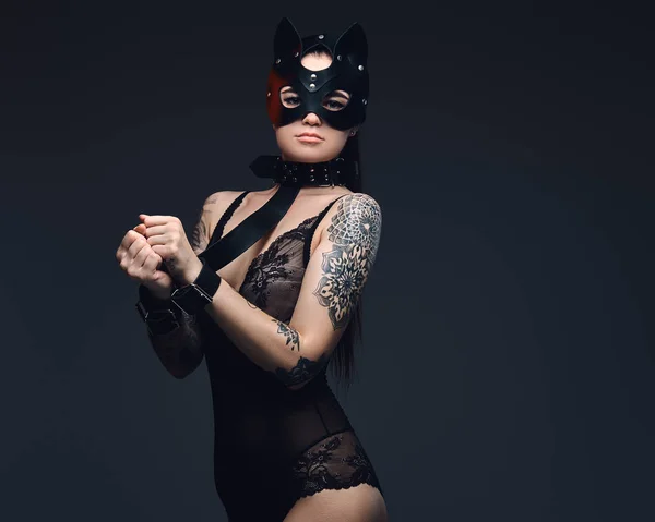 Femme sexy portant de la lingerie noire en cuir de chat BDSM masque et accessoires posant sur fond sombre . — Photo