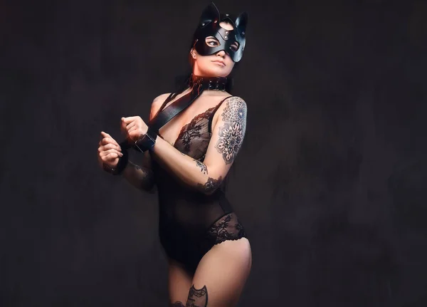 Donna sexy che indossa lingerie nera in maschera di pelle di gatto BDSM e accessori in posa su sfondo scuro . — Foto Stock