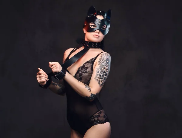 Donna sexy che indossa lingerie nera in maschera di pelle di gatto BDSM e accessori in posa su sfondo scuro . — Foto Stock