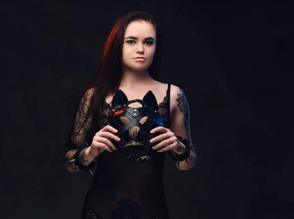 Sexy žena na sobě černé spodní prádlo v Bdsm maska kůže a příslušenství představuje na tmavém pozadí. — Stock fotografie