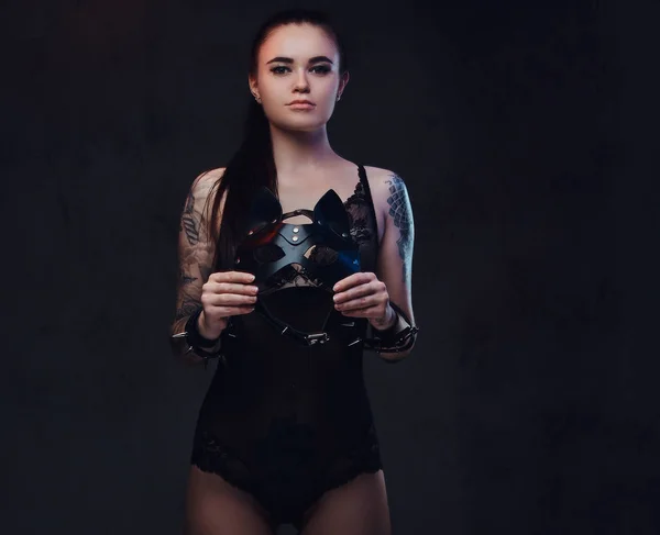 Sexy Frau trägt schwarze Dessous in bdsm Katzenledermaske und Accessoires posiert auf dunklem Hintergrund. — Stockfoto