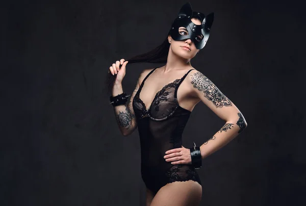 Sexy vrouw dragen zwarte lingerie in Bdsm kat lederen masker en accessoires die zich voordeed op donkere achtergrond. — Stockfoto