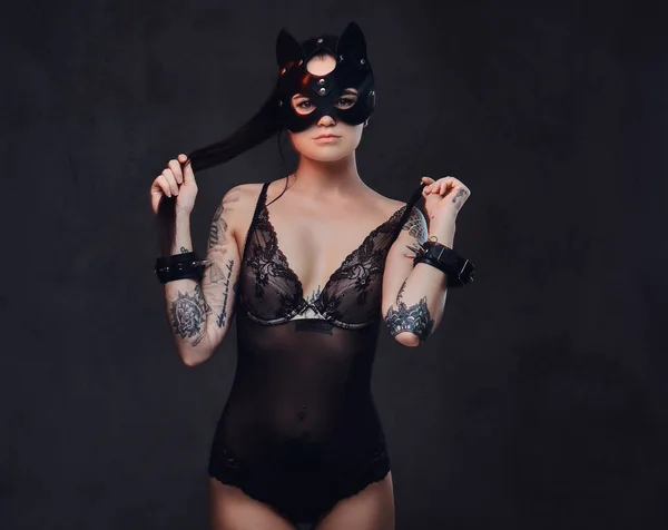 Sexig kvinna klädd i svart underkläder i Bdsm katt läder mask och tillbehör poserar på mörk bakgrund. — Stockfoto