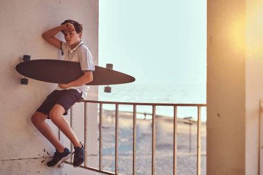 Günbatımında bir Otokorkuluk bir sahil arka planı üzerinde otururken bir kaykay bir genç kaykaycı çocuk portresi tutar.