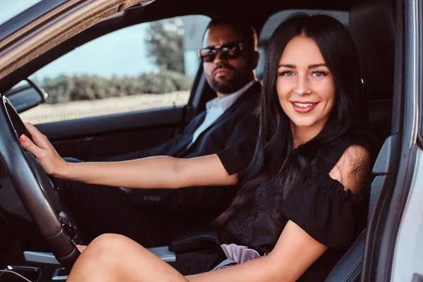 Hermosa pareja bien vestida sentada en los asientos delanteros en el coche de lujo . —  Fotos de Stock