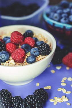 Sağlıklı kahvaltı. Beyaz tabak yulaf ezmesi mayınları ve mavi bir arka plan üzerinde farklı meyveler ile. Yaz hasat.