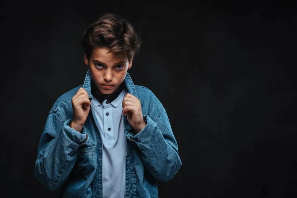 Jeune homme à la mode vêtu d'un t-shirt et d'une veste en jean posant dans un studio . — Photo