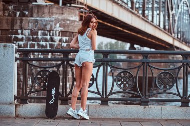 Şort ve tişört üzerinde bir dolgu, Otokorkuluk yaslanmış bir şehvetli patenci kız arkadan görünüm giymiş.