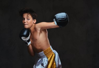 Yakışıklı gömleksiz genç boksör boks egzersizleri sırasında ciddi konsantre yüz ile süreci odaklı. Koyu arka plan üzerinde izole.