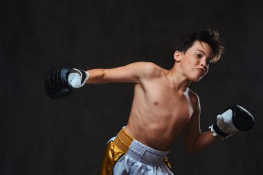 Yakışıklı gömleksiz genç boksör boks egzersizleri sırasında ciddi konsantre yüz ile süreci odaklı. Koyu arka plan üzerinde izole.