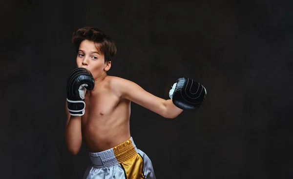 Красивый молодой боксер без рубашки во время боксёрских упражнений, сосредоточенный на процессе с серьезным концентрированным лицом. Изолированный на тёмном фоне . — стоковое фото