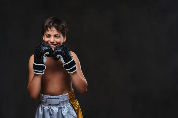 Jovem boxeador sem camisa, feliz e bonito, usando luvas. Isolado em um fundo escuro . — Fotografia de Stock