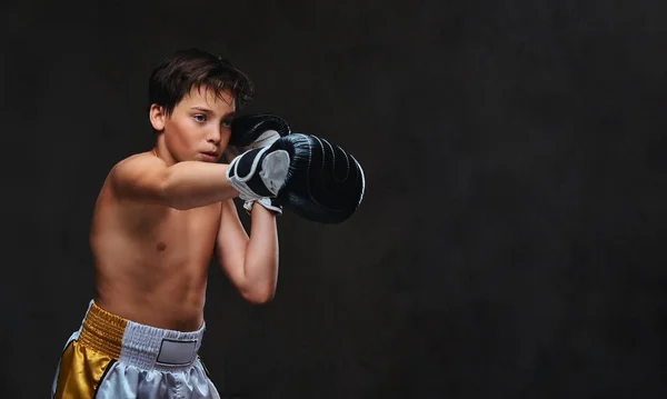 Handsome shirtless young boxer during boxing exercises, focused on process with serious concentrated facial. Isolated on the dark background. — Stock Photo, Image