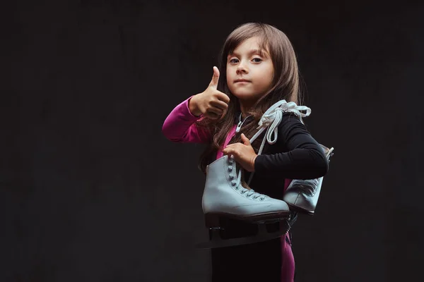 Σίγουρη κοριτσάκι ντυμένη με αθλητικά δείχνει τους αντίχειρες. Απομονωμένα σε σκούρο φόντο με υφή. — Φωτογραφία Αρχείου