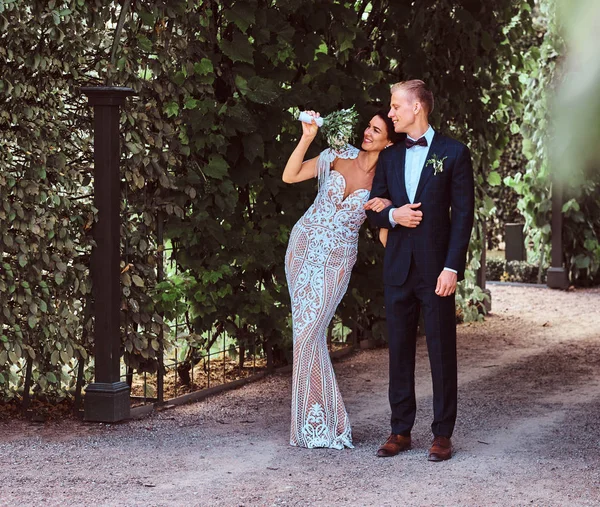 Heureux couple de mariage se promène par un beau jardin . — Photo