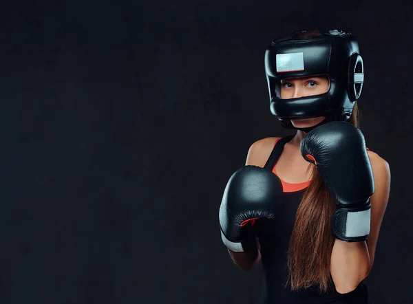 Retrato de cerca de una boxeadora con guantes y casco protector posando en un estudio. Aislado sobre fondo de textura oscura . —  Fotos de Stock