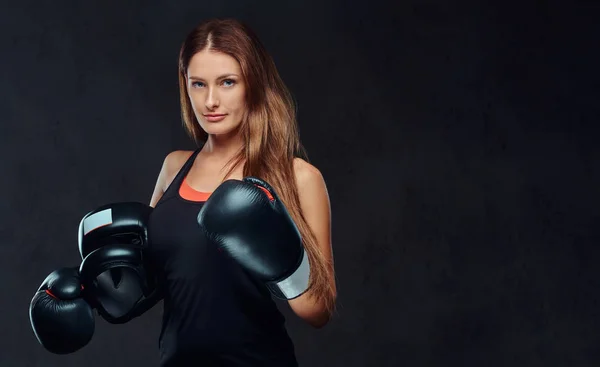 Retrato de una boxeadora usando guantes sostiene un casco protector posando en un estudio. Aislado sobre fondo de textura oscura . —  Fotos de Stock