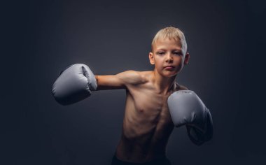 Gömleksiz genç boksör boks eldivenli sarı saçlı bir boks kanca gösterir.