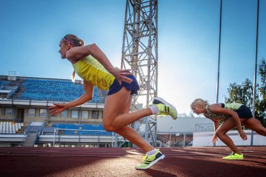 Atletizm Stadyumu eğitim sırasında koşu yarışı üzerinde çalışan iki kadın sprinter sporcular.