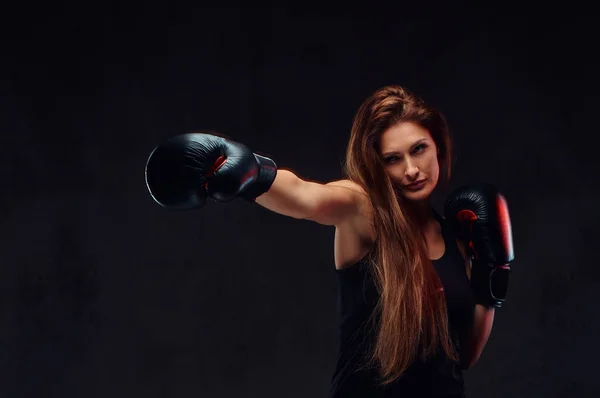 Mooie brunette vrouwelijke bokser tijdens boksen oefeningen, gericht op een proces met ernstige geconcentreerde facial. — Stockfoto