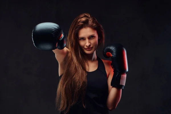 Belle brune boxeuse lors d'exercices de boxe, entraînement en salle de gym. Isolé sur fond texturé foncé . — Photo