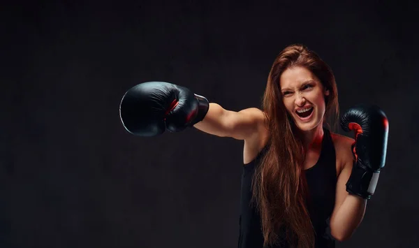 Boxeadora femenina morena deportiva durante ejercicios de boxeo, enfocada en el proceso con facial agresivo . —  Fotos de Stock