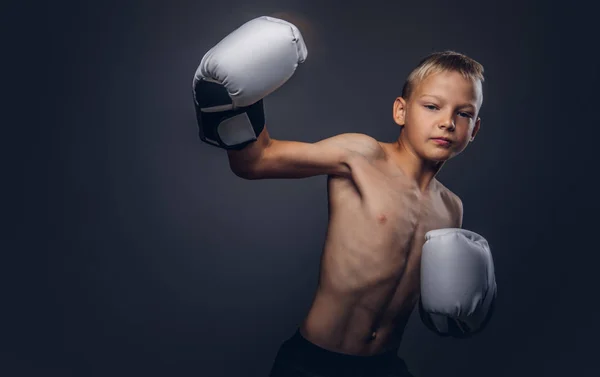 Boxeador joven sin camisa con pelo rubio usando guantes de boxeo muestra un gancho de boxeo . —  Fotos de Stock
