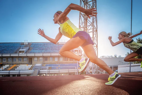 Två kvinnliga sprinter idrottare kör på löpband loppet under träning i friidrottsarena. — Stockfoto