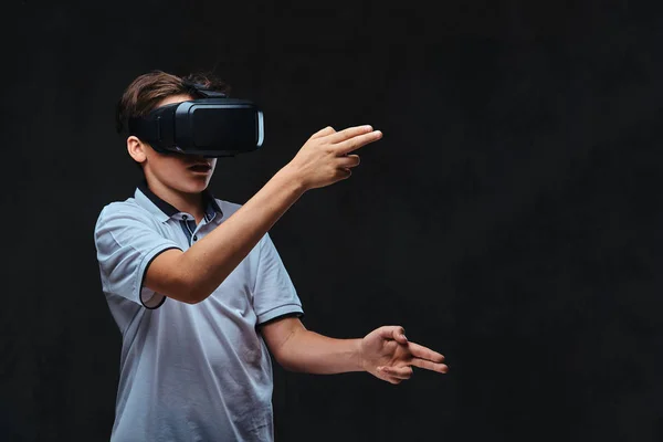 Tiener gekleed in een wit t-shirt spelen met een vr bril. Geïsoleerd op de donkere achtergrond. — Stockfoto
