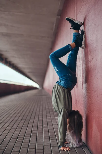 女子高生が橋の通行で壁にもたれて逆立ちして立っています — ストック写真