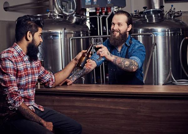 Interracial 양조장에 앞치마에 문신된 Hipster 작업자 공장에 친구와 맥주를 마신다 — 스톡 사진
