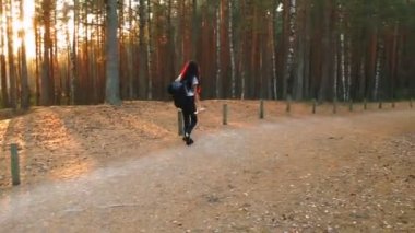 Güzel bir sonbahar ormanda yürürken termos ve yoga mat t-shirt ve sırt çantası ile pantolon giymiş güzel kız tutar.