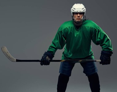 Tam dişli ve hokey sopası giyen profesyonel hokey oyuncusu portresi. Gri bir arka plan üzerinde izole.