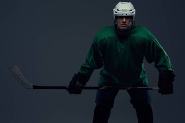 Tam dişli ve hokey sopası giyen profesyonel hokey oyuncusu portresi. Gri bir arka plan üzerinde izole.