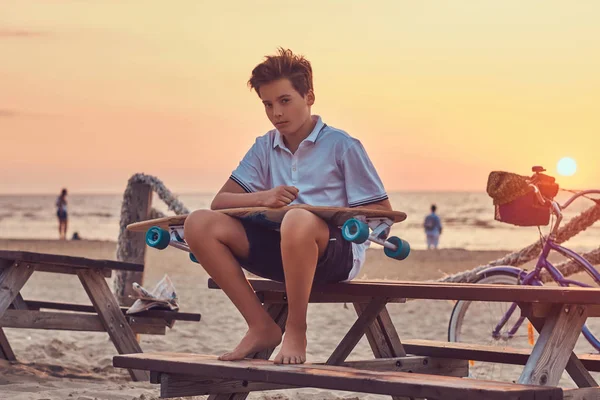 Młody Skater Boy Ubrany Koszulkę Szorty Siedząc Ławce Tle Seacoast — Zdjęcie stockowe