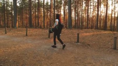 Güzel bir sonbahar ormanda yürürken termos ve yoga mat t-shirt ve sırt çantası ile pantolon giymiş güzel kız tutar.