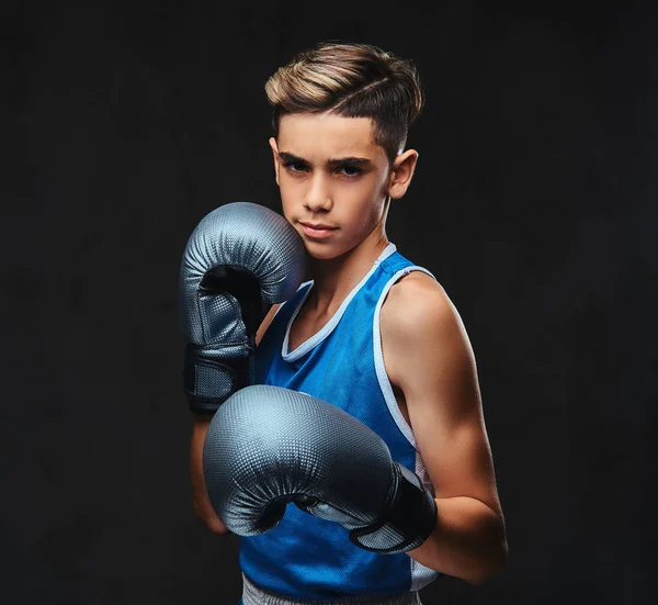 Spor giyim eldiven giymiş yakışıklı bir genç boksör portresi. Karanlık bir arka plan üzerinde izole.