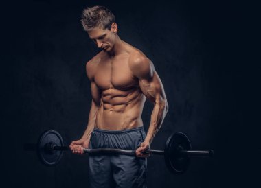 Yakışıklı gömleksiz adam şık saç ve kas ectomorph karanlık dokulu bir arka plan üzerinde halter ile egzersizleri yapıyor.