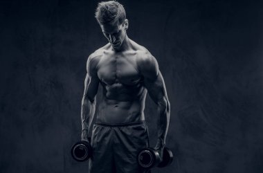 Siyah ve beyaz fotoğraf aşağı koyu arka plan üzerinde halter ve bakışlarla poz ectomorph vücut geliştirmeci.