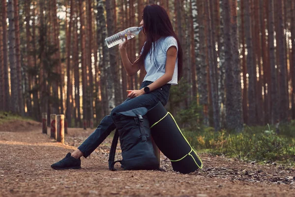 Tourist girl stopped to rest and drink water in the beautiful autumn forest. — Stock Photo, Image