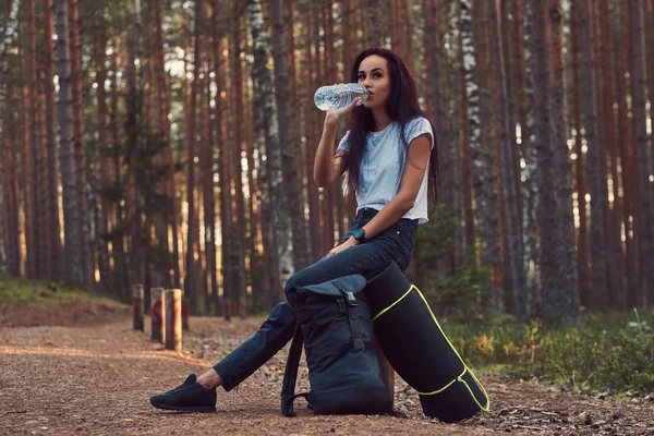 Chica turística se detuvo a descansar y beber agua en el hermoso bosque de otoño . — Foto de Stock