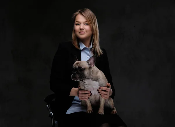 Happy blonde woman breeder sitting on a chair and holds her cute pug. — Stock Photo, Image