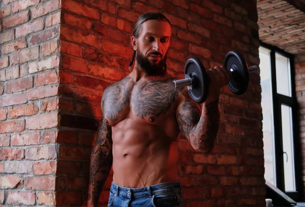 Acımasız sakallı dövmeli erkek çatı iç ile bir odada bir dumbbell ile egzersiz yaparak. — Stok fotoğraf