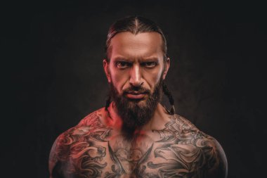 Yakın çekim fotoğraf bir acımasız gömleksiz dövmeli erkek sakallı. Karanlık dokulu bir arka plan üzerinde izole.