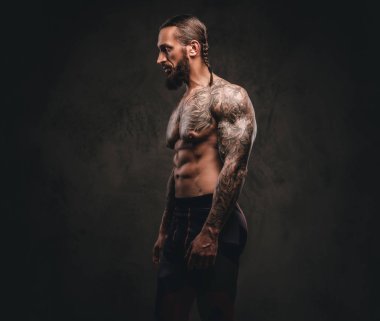 Spor giyim bir sakallı dövmeli sporcu profili. Karanlık dokulu arka plan üzerinde izole.